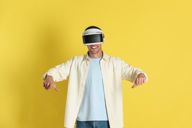 Photo of Smiling man using virtual reality headset on yellow background
