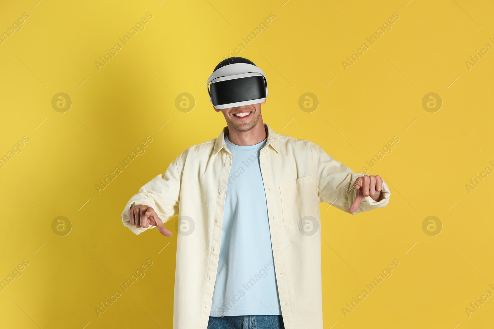 Photo of Smiling man using virtual reality headset on yellow background