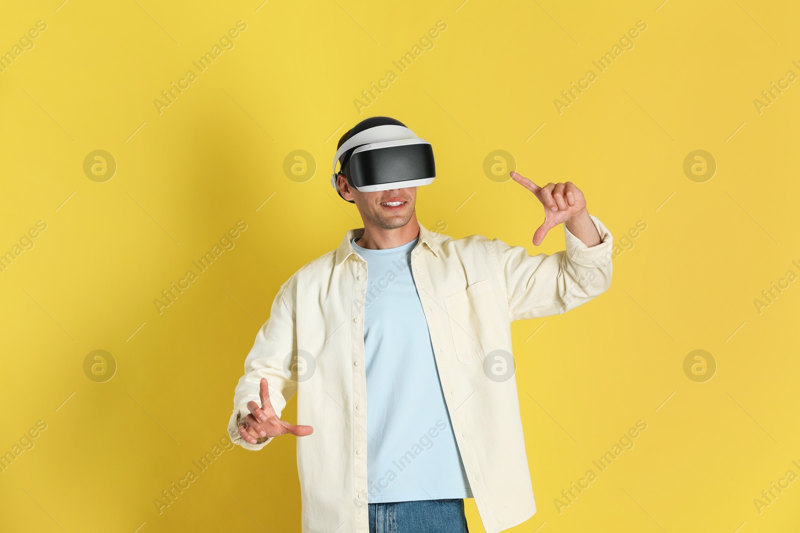 Photo of Man using virtual reality headset on yellow background