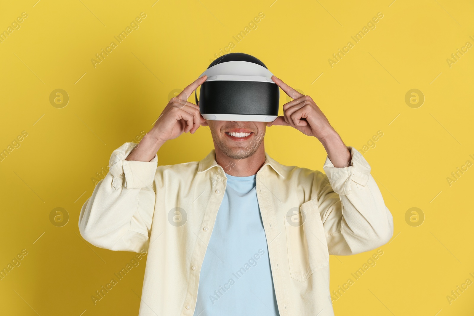 Photo of Smiling man using virtual reality headset on yellow background