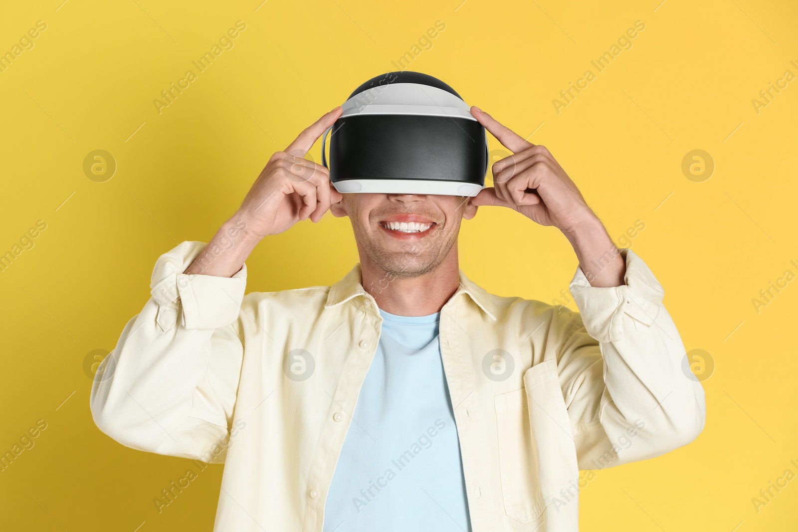 Photo of Smiling man using virtual reality headset on yellow background