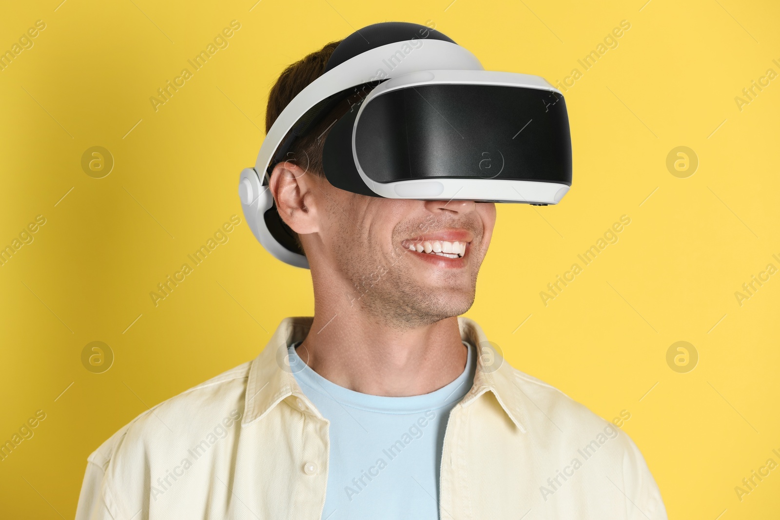 Photo of Smiling man using virtual reality headset on yellow background