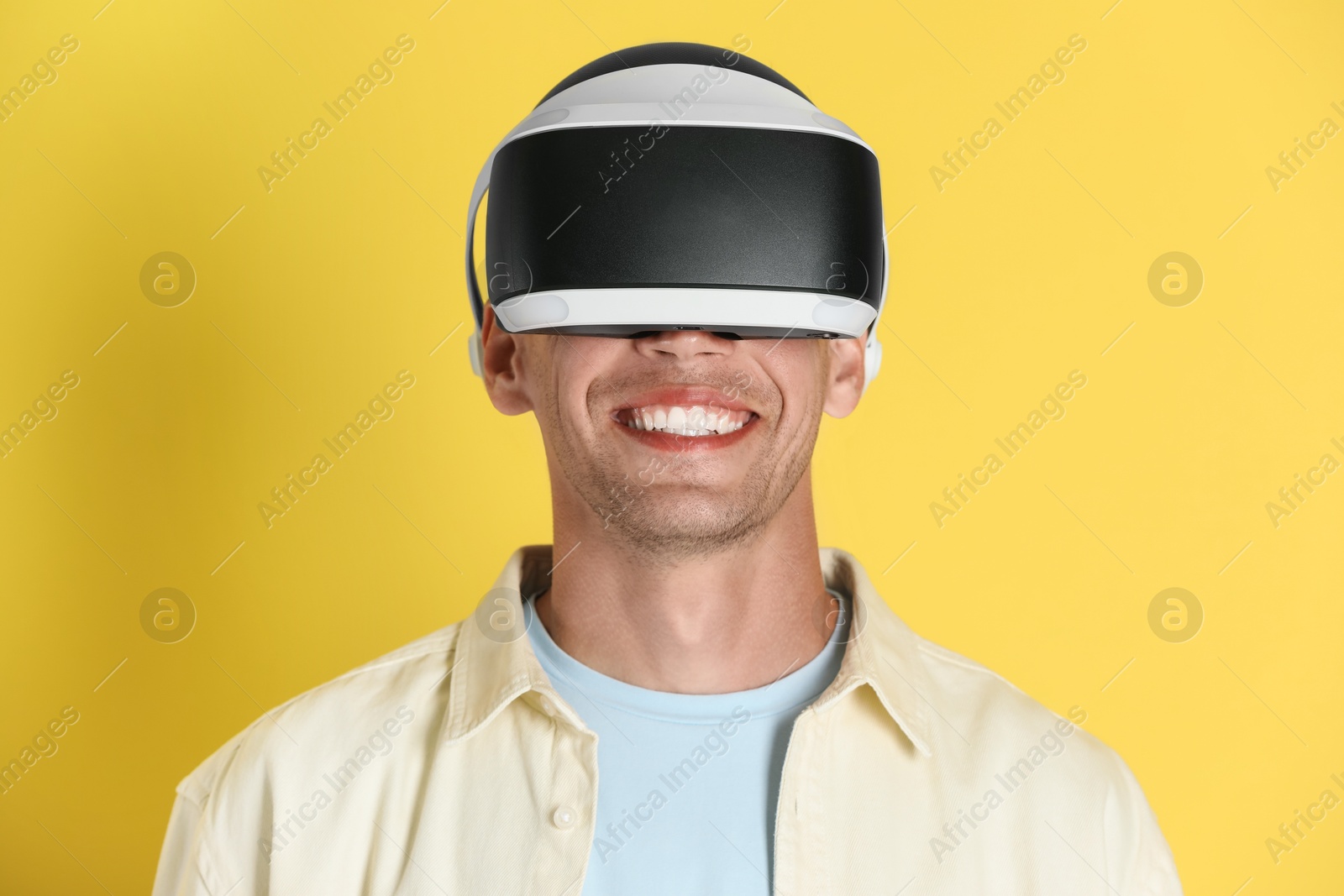 Photo of Smiling man using virtual reality headset on yellow background