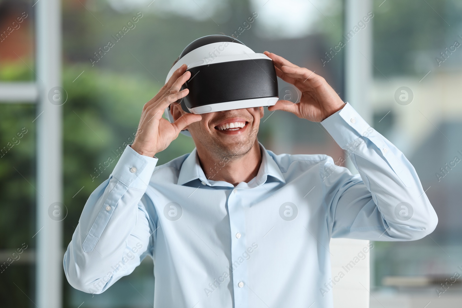 Photo of Smiling man using virtual reality headset in office