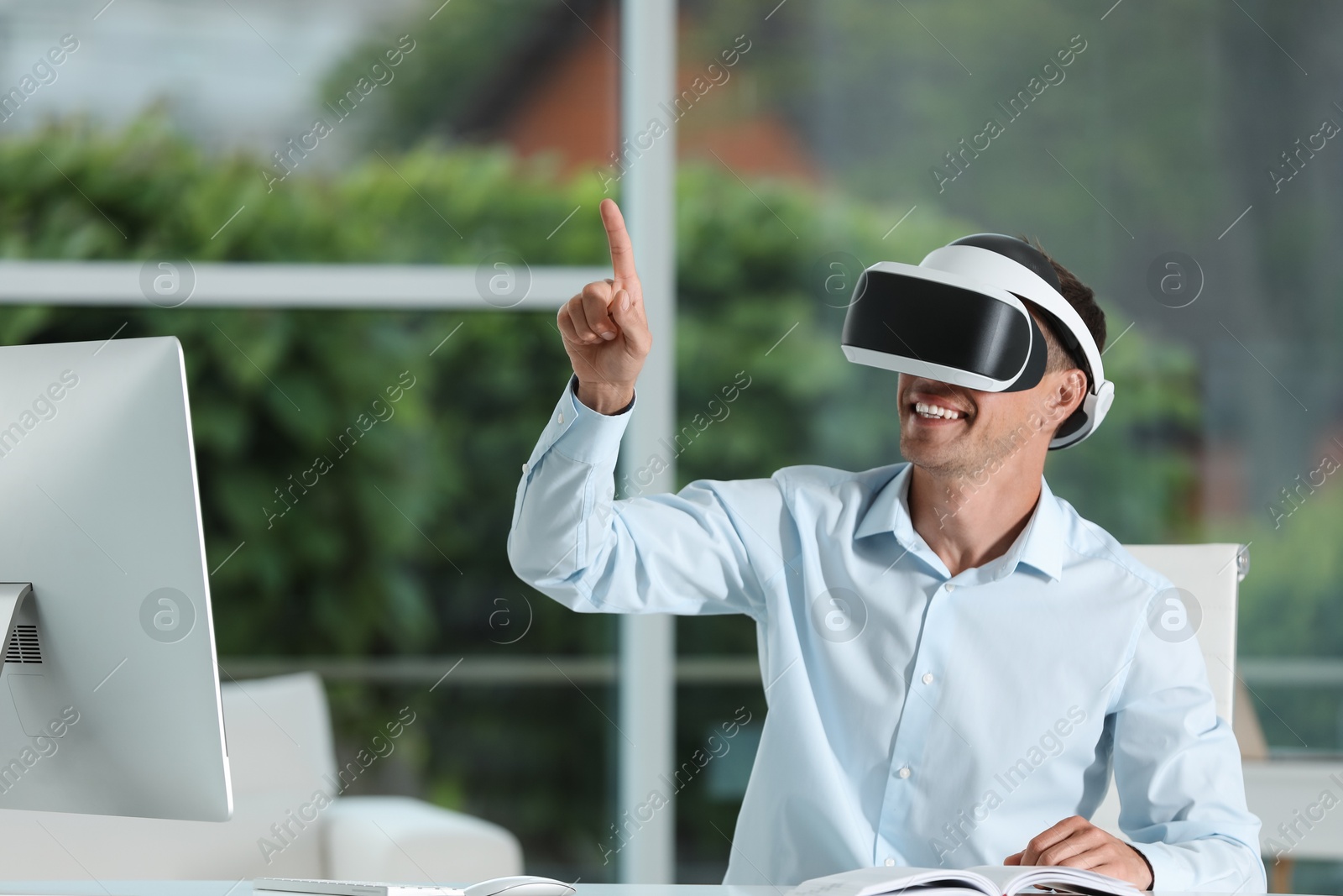 Photo of Smiling man using virtual reality headset in office