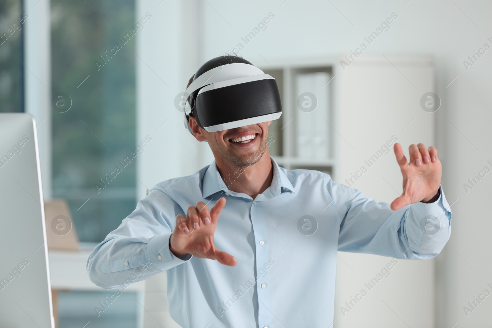 Photo of Smiling man using virtual reality headset in office