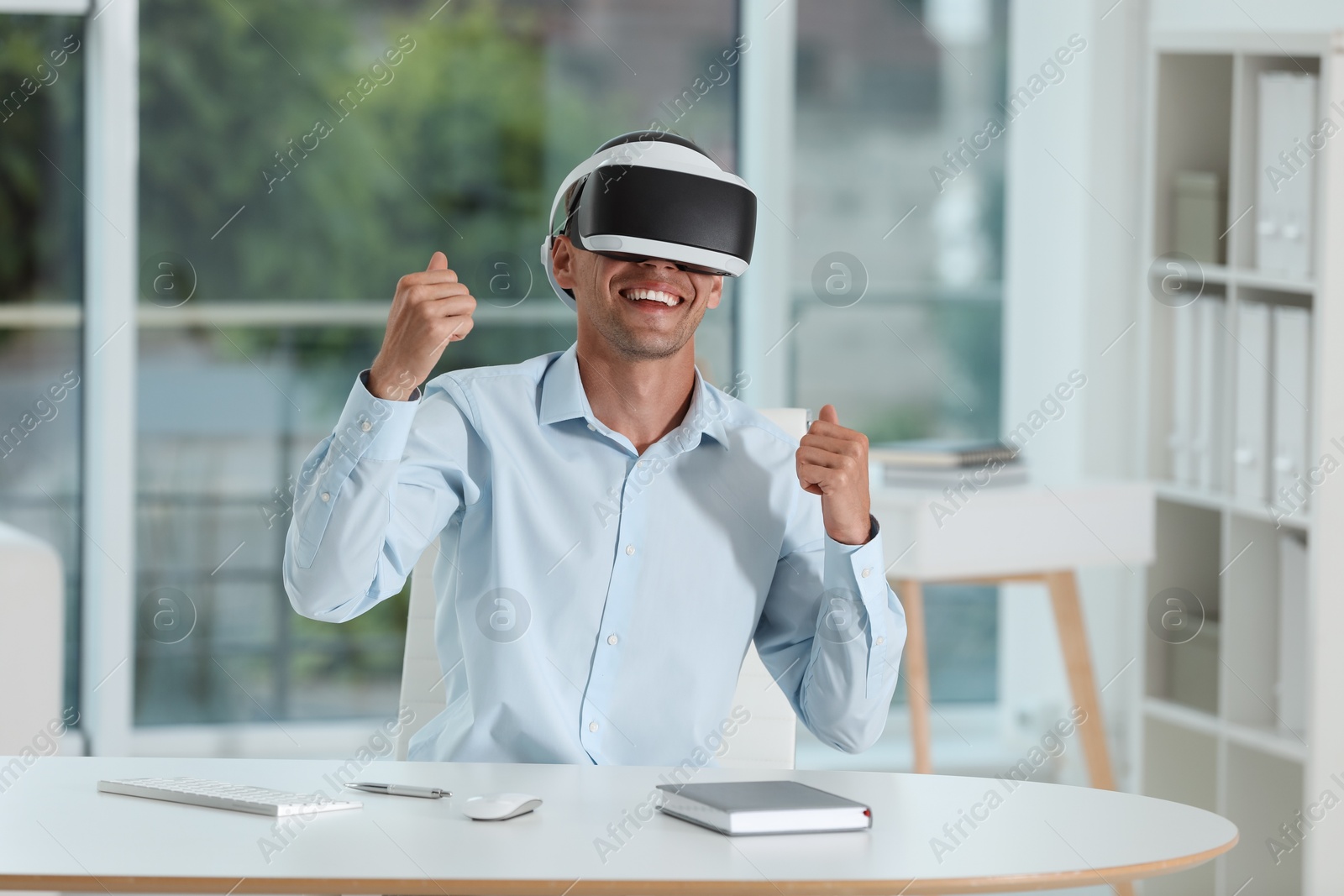 Photo of Smiling man using virtual reality headset in office