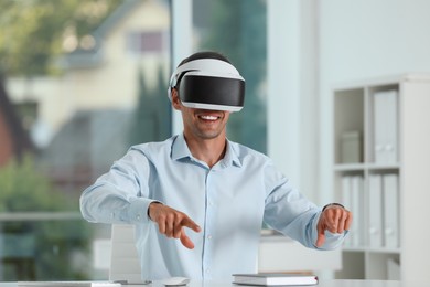 Photo of Smiling man using virtual reality headset in office