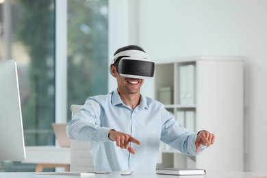 Photo of Smiling man using virtual reality headset in office