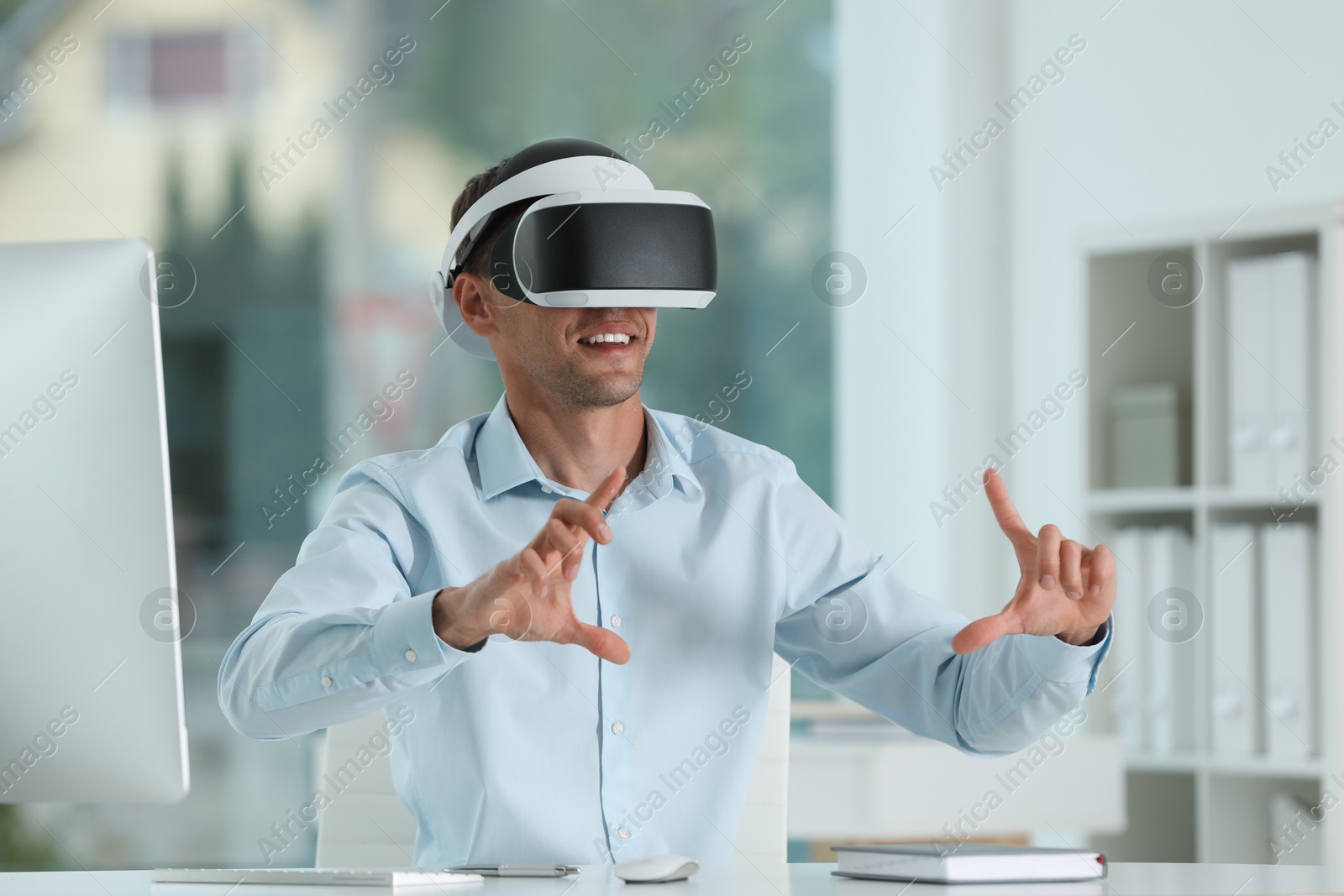 Photo of Smiling man using virtual reality headset in office