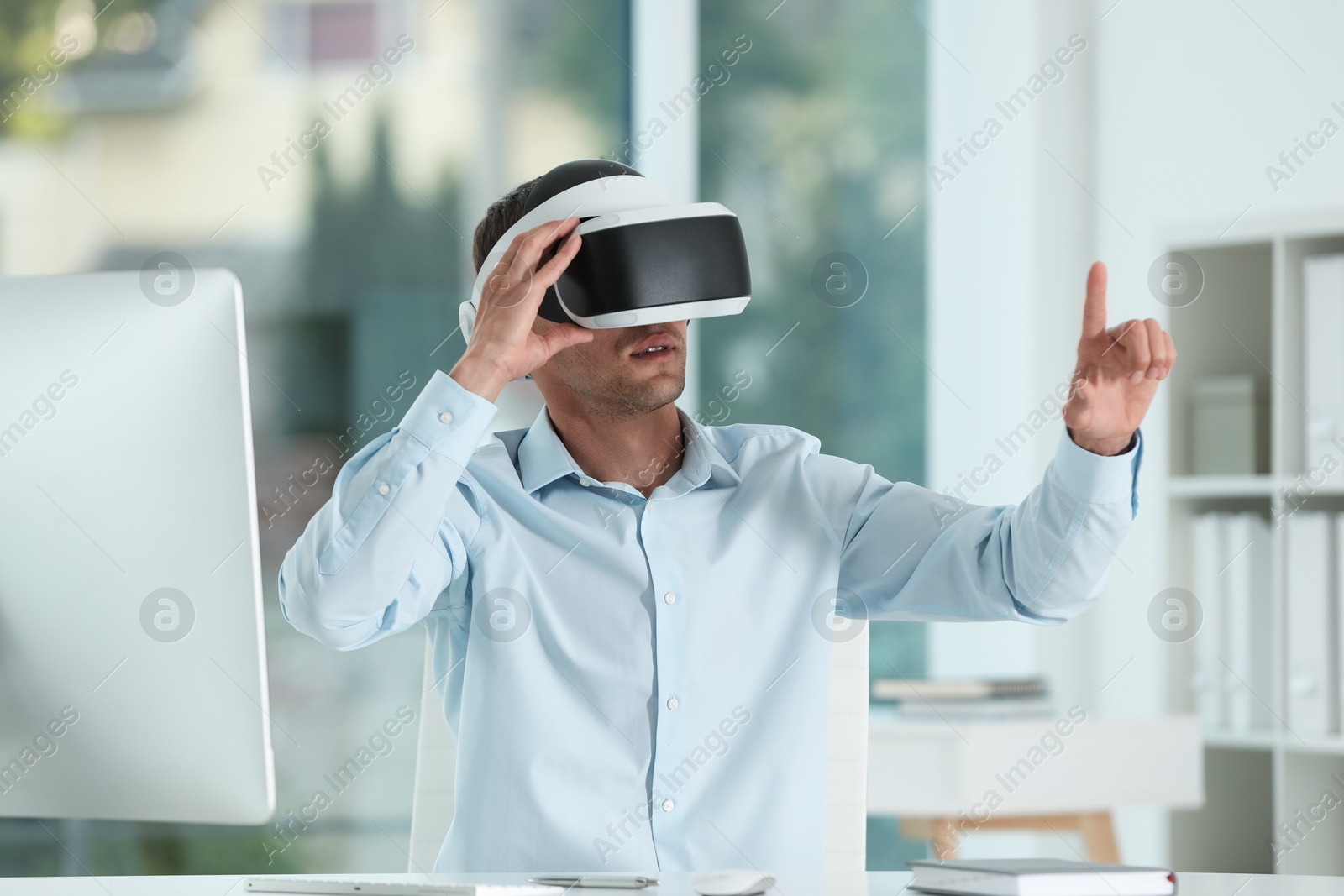 Photo of Man using virtual reality headset in office