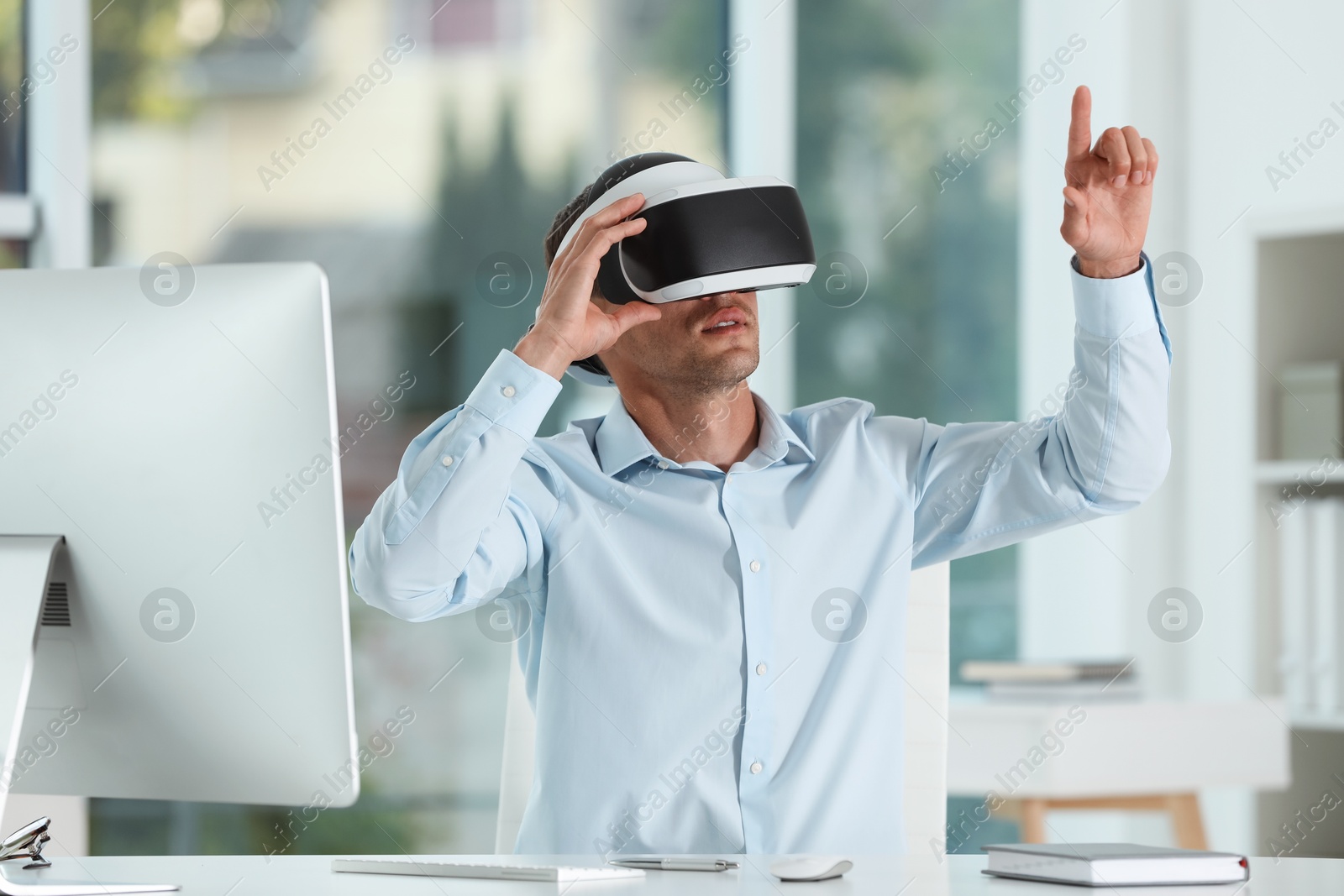 Photo of Man using virtual reality headset in office