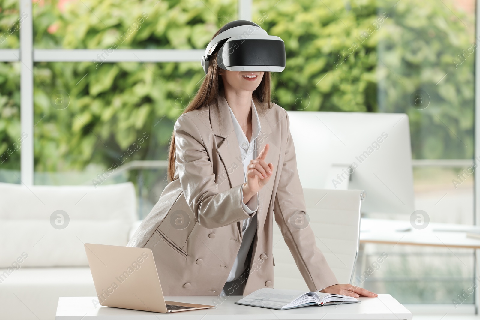 Photo of Smiling woman using virtual reality headset in office