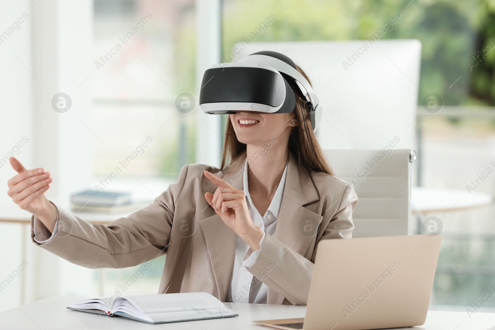 Photo of Smiling woman using virtual reality headset in office