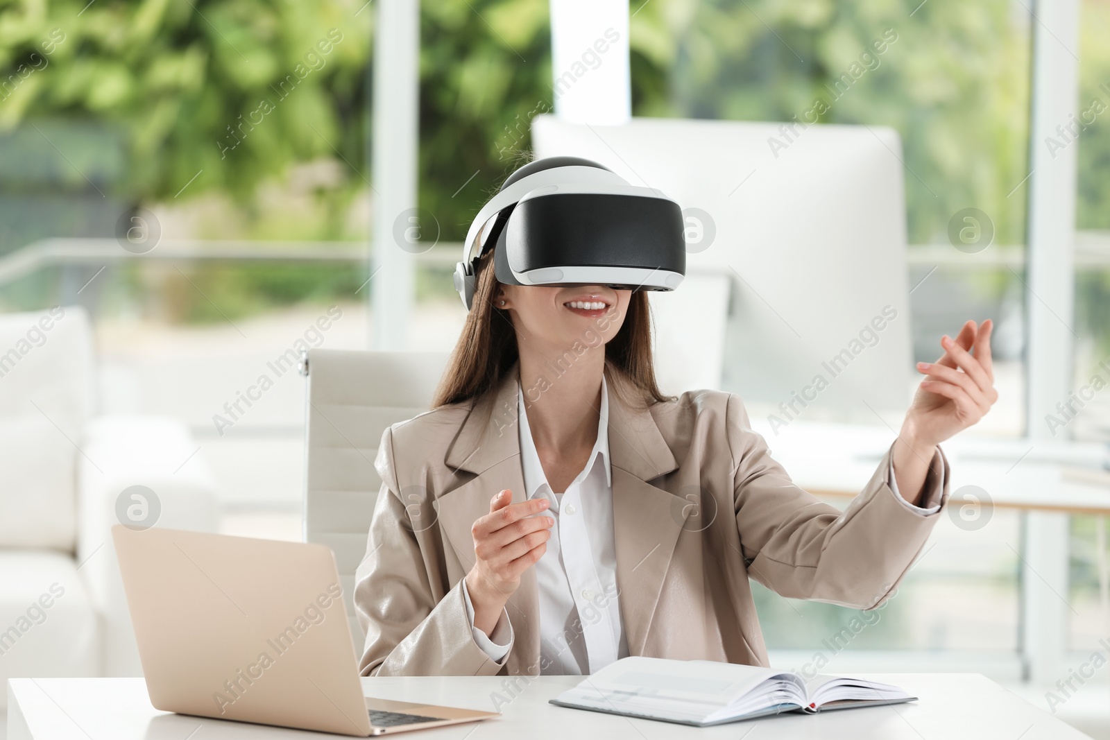 Photo of Smiling woman using virtual reality headset in office