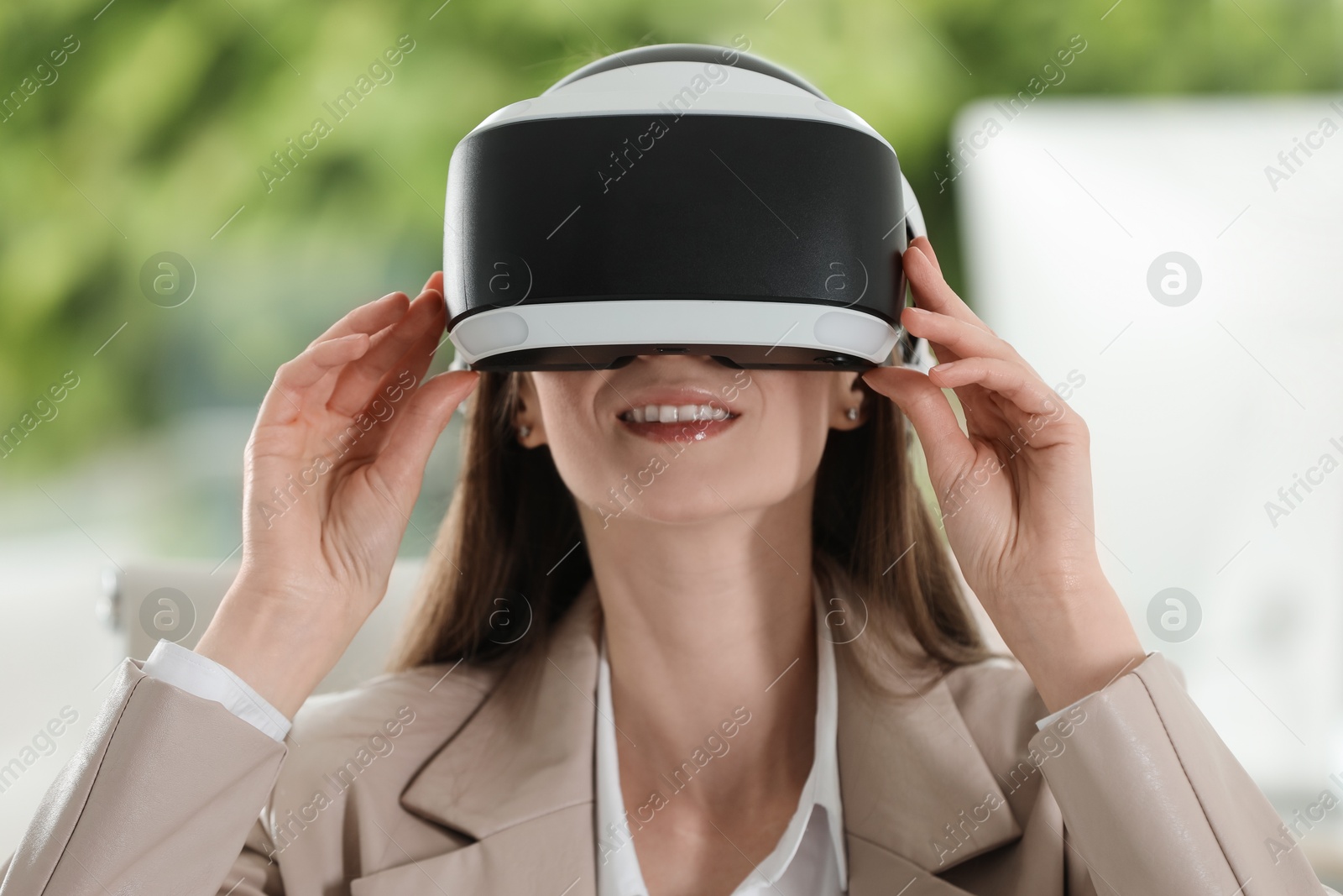 Photo of Smiling woman using virtual reality headset in office