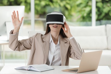Photo of Woman using virtual reality headset in office