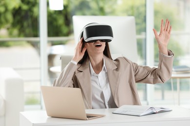 Photo of Surprised woman using virtual reality headset in office