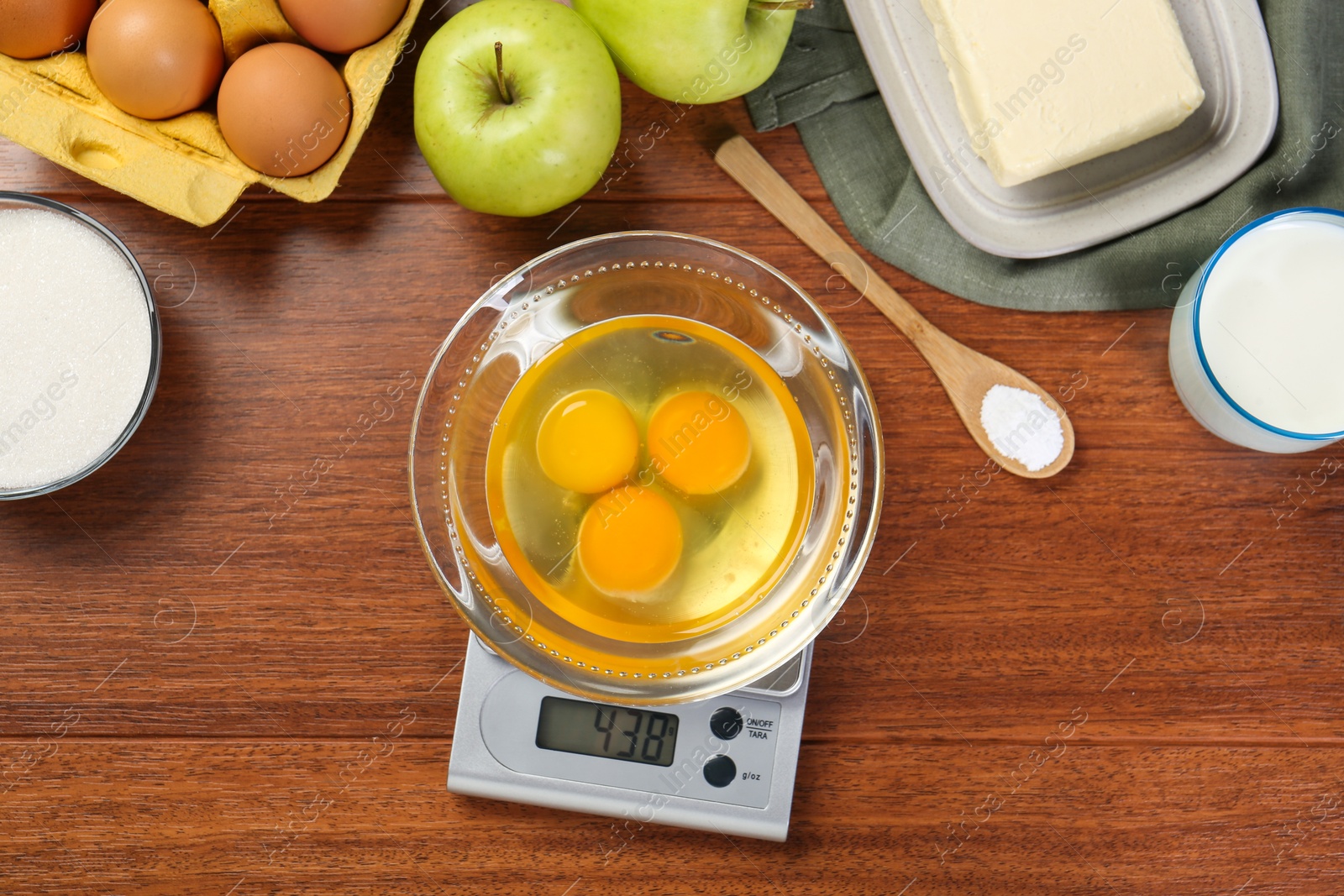 Photo of Flat lay composition of kitchen scale with bowl of raw eggs on wooden table