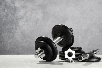 Barbell and parts of one on light table against grey background. Space for text