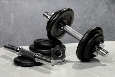 Barbell and parts of one on light table against grey background