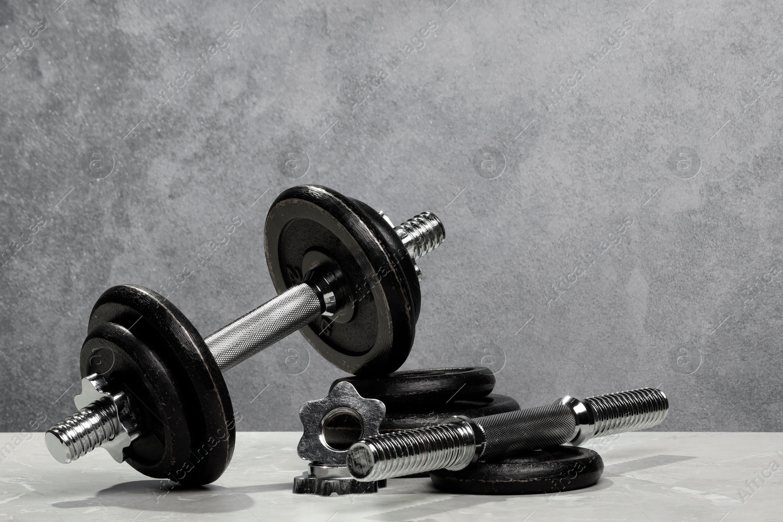 Photo of Barbell and parts of one on light table against grey background. Space for text