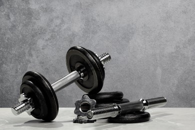 Photo of Barbell and parts of one on light table against grey background. Space for text