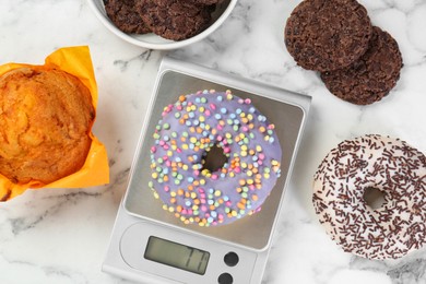 Photo of Flat lay composition of kitchen scale with donut on white marble table