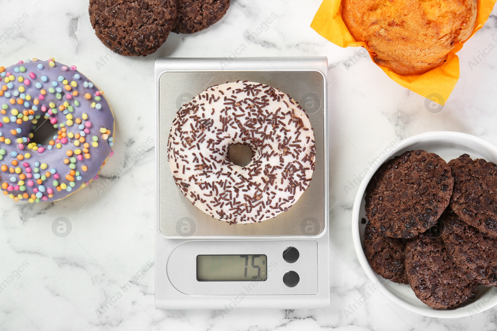 Photo of Flat lay composition of kitchen scale with donut on white marble table