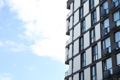 Photo of Modern building with big windows against blue sky outdoors, space for text