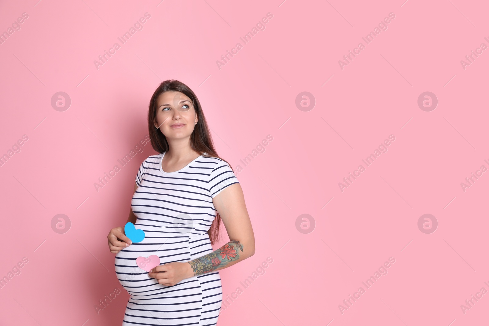 Photo of Beautiful pregnant woman with paper hearts on pink background, space for text. Expecting twins