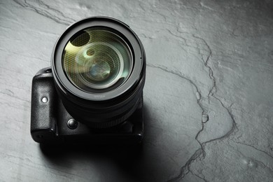 Modern photo camera on black table, above view. Space for text