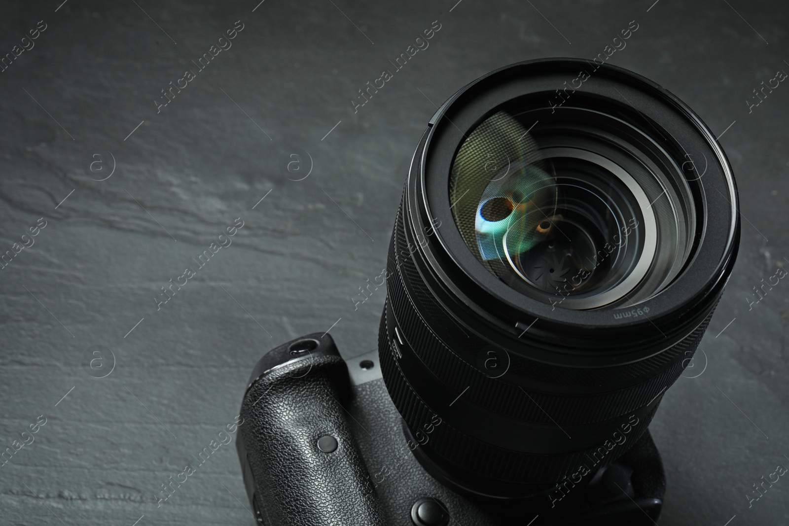 Photo of Modern photo camera on black table, closeup. Space for text