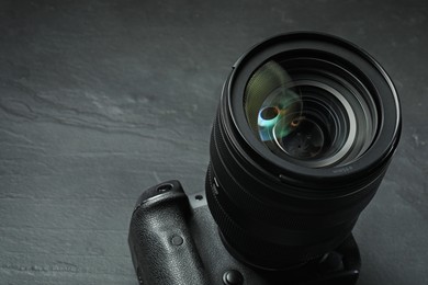 Photo of Modern photo camera on black table, closeup. Space for text