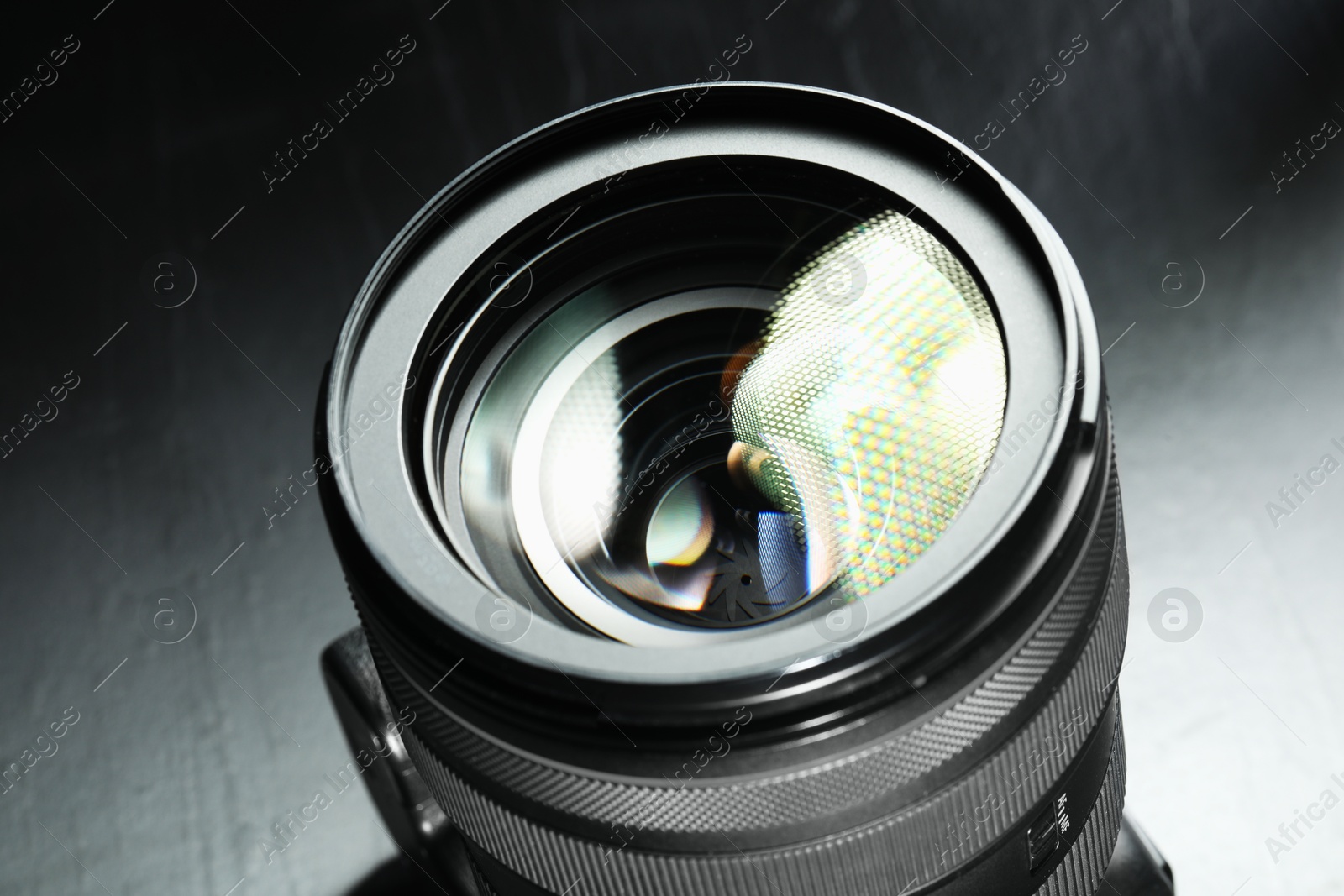 Photo of Modern camera lens on black table, closeup