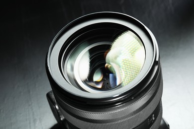 Photo of Modern camera lens on black table, closeup