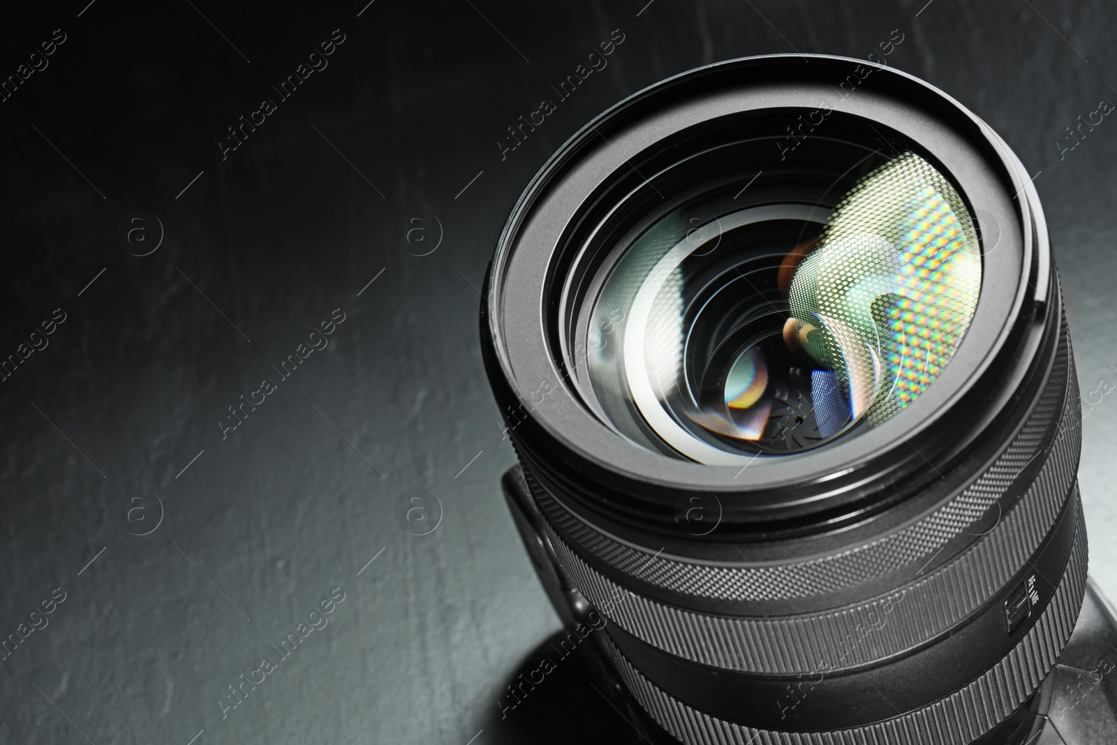 Photo of Modern camera lens on black table, closeup. Space for text