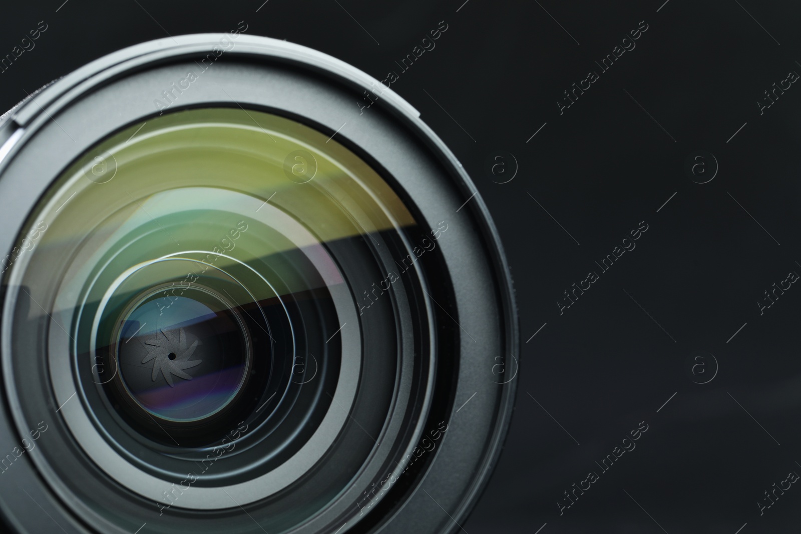 Photo of Modern camera lens on black table, closeup. Space for text