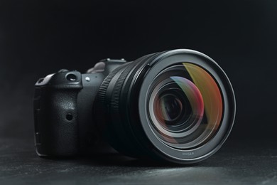 Modern photo camera on black table, closeup. Photographer's equipment