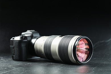 Modern photo camera on black table. Photographer's equipment