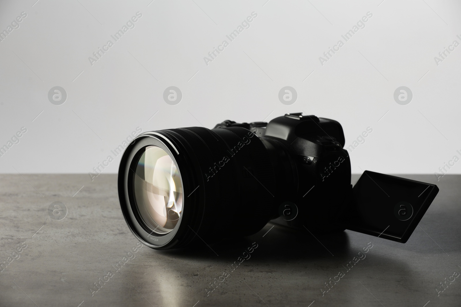 Photo of Modern photo camera on grey table. Photographer's equipment