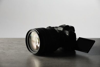 Modern photo camera on grey table. Photographer's equipment