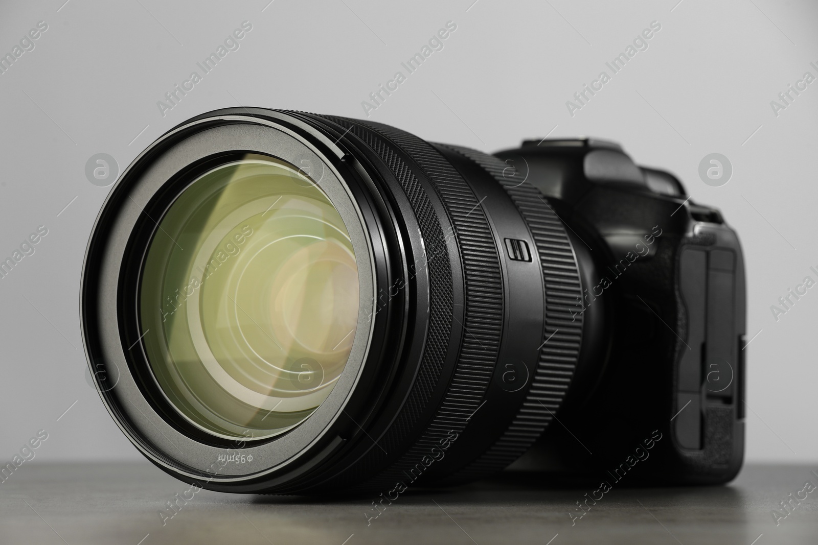 Photo of Modern photo camera on grey table, closeup. Photographer's equipment