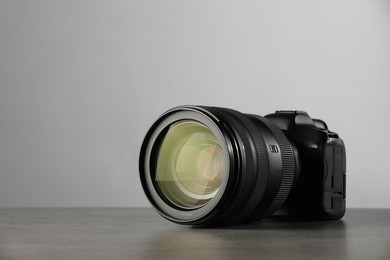 Modern photo camera on grey table, space for text. Photographer's equipment