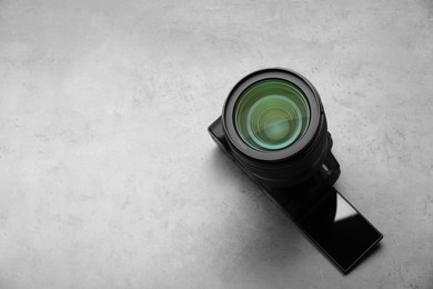 Modern photo camera on grey table, above view and space for text. Photographer's equipment