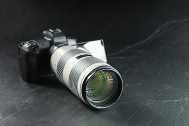 Photo of Modern photo camera on black table, space for text