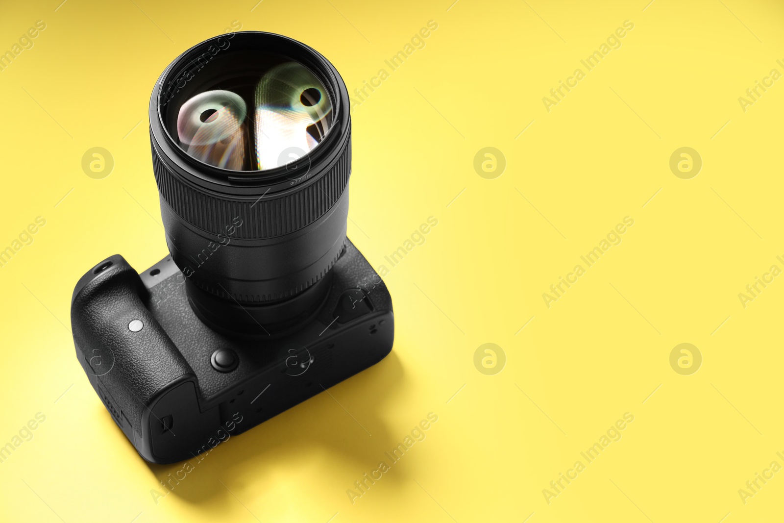 Photo of One modern photo camera on yellow background, space for text