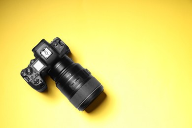 Photo of One modern photo camera on yellow background, top view. Space for text