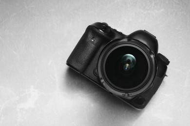 Photo of Modern photo camera on light grey marble table, top view. Space for text