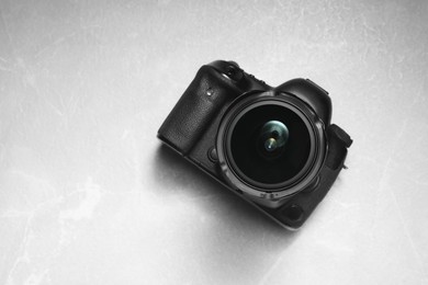 Modern photo camera on light grey marble table, top view. Space for text